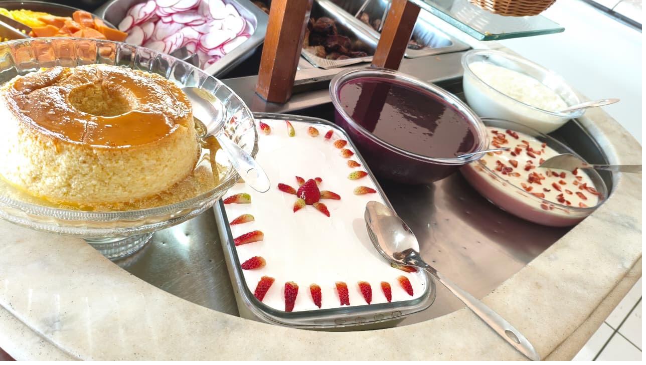 Pudim com calda de caramelo ao lado de uma sobremesa gelada decorada com morangos
